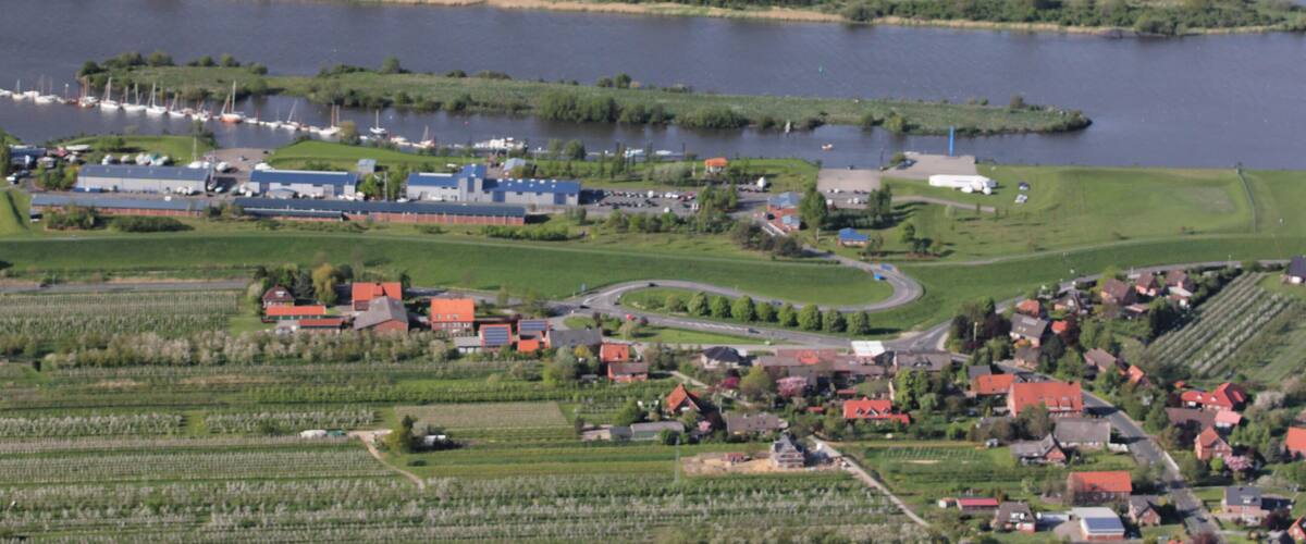 A lakeside village with boats, houses, and agricultural fields.