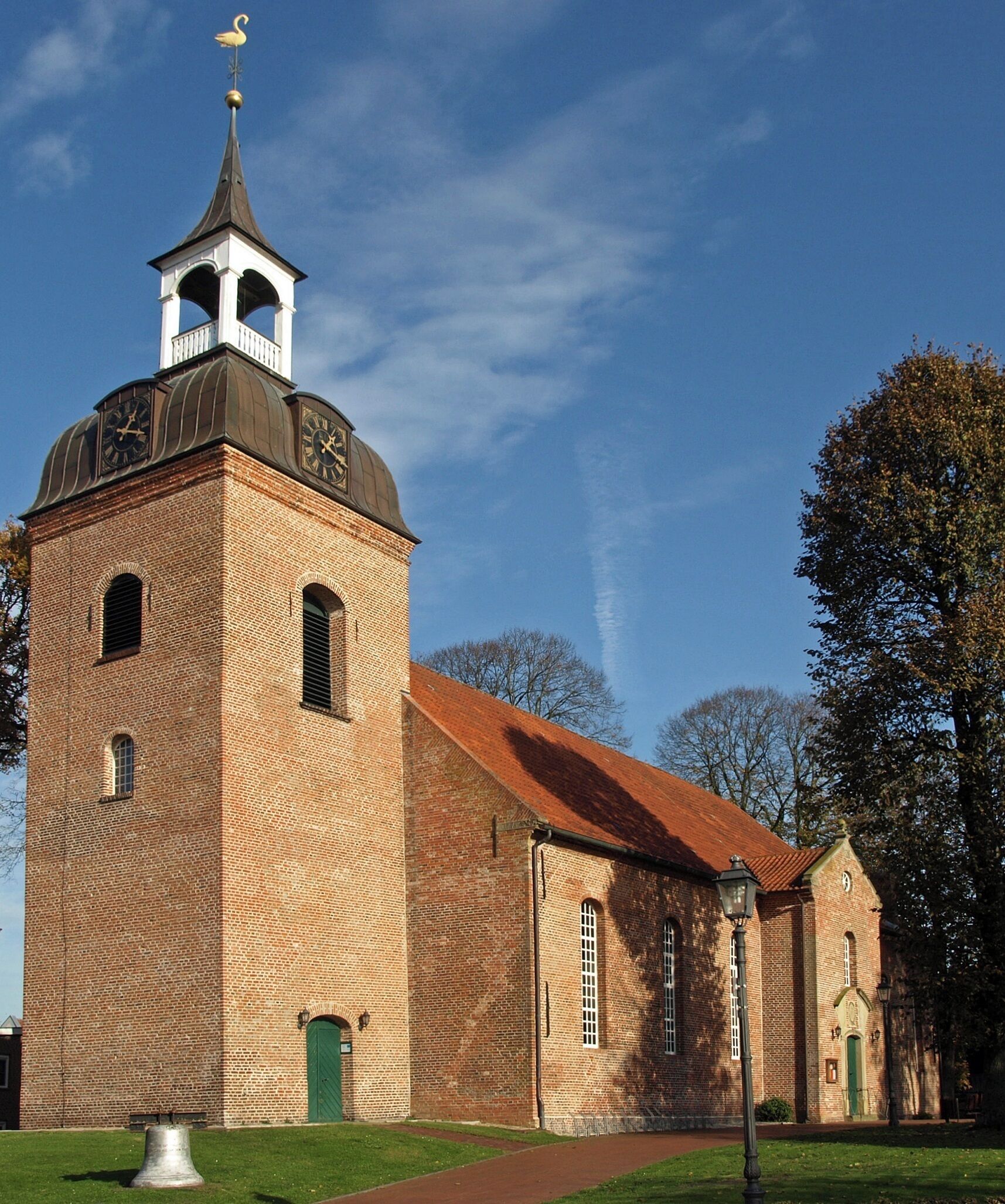 A historic church with a bell tower, brick walls, and a red roof.