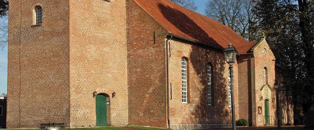 A historic church with a bell tower, brick walls, and a red roof.