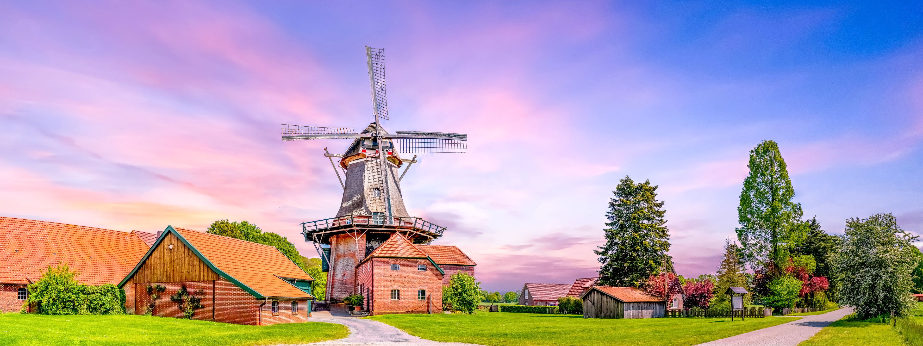 A windmill, a brick building, and a tall tree.