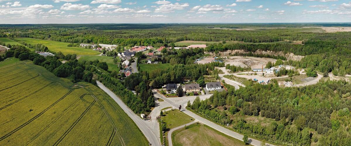An aerial view of a rural area with fields, a small village, and a construction site.