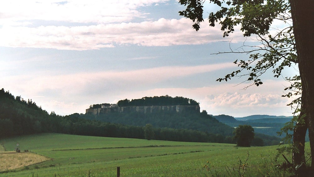 A castle on a hill surrounded by green fields.