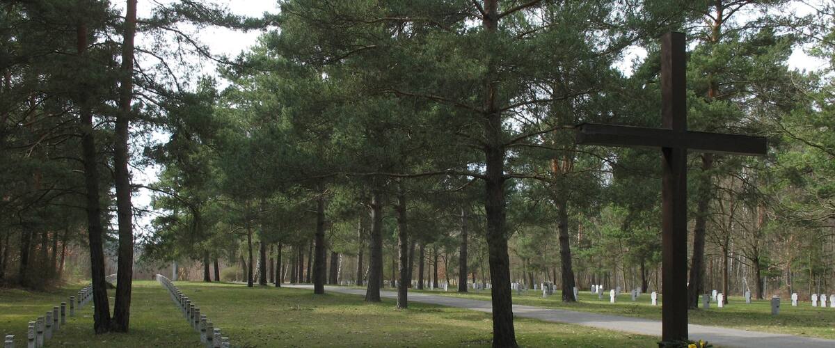 A cemetery with a cross, gravestones, and a path.