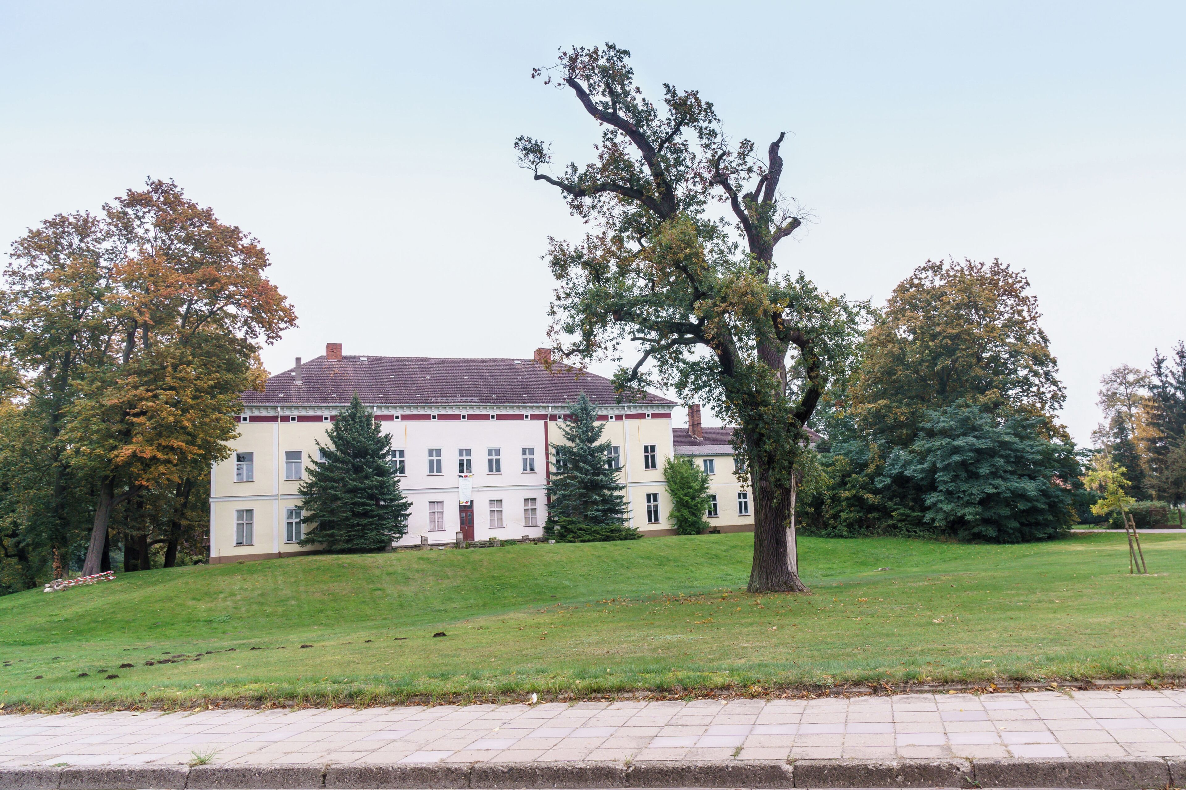 A large building with a red roof, surrounded by trees and a grassy area.