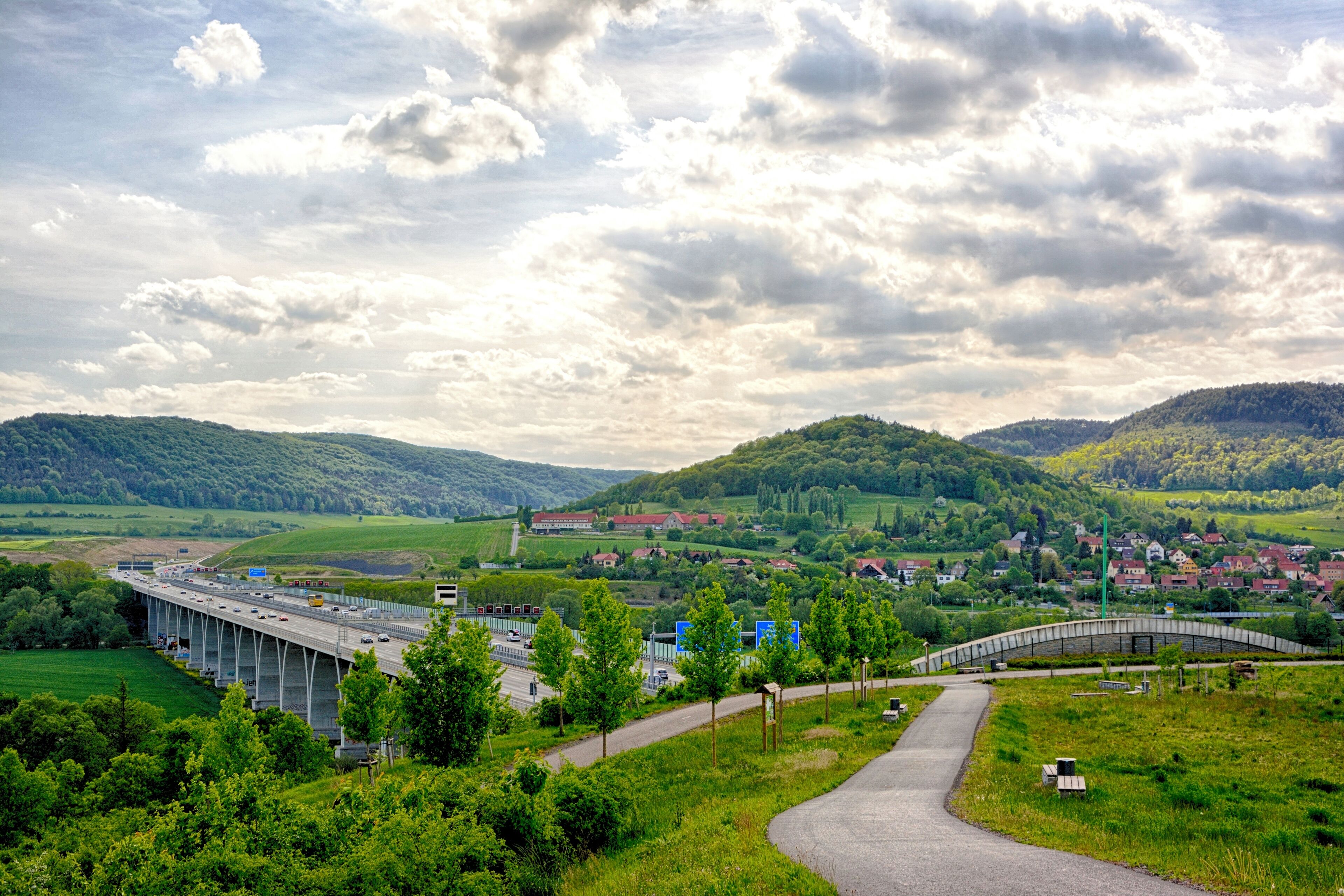 A bridge over a river, surrounded by green hills and a small town.