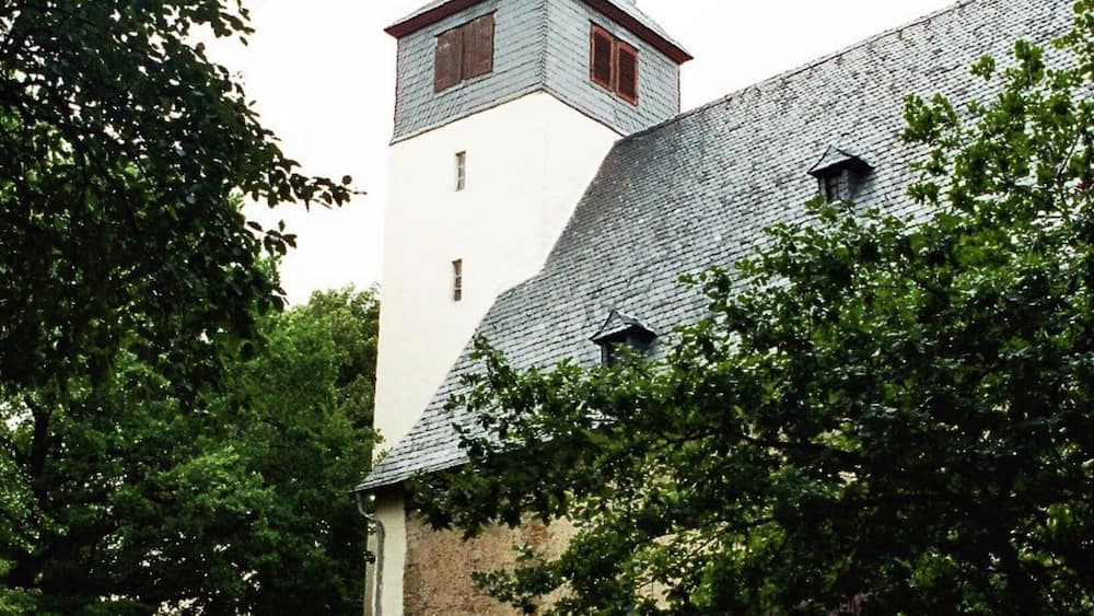 Eine Kirche mit einem hohen Kirchturm und einem Steindenkmal im Vordergrund.