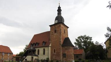 A church with a tall tower and a cemetery with headstones.