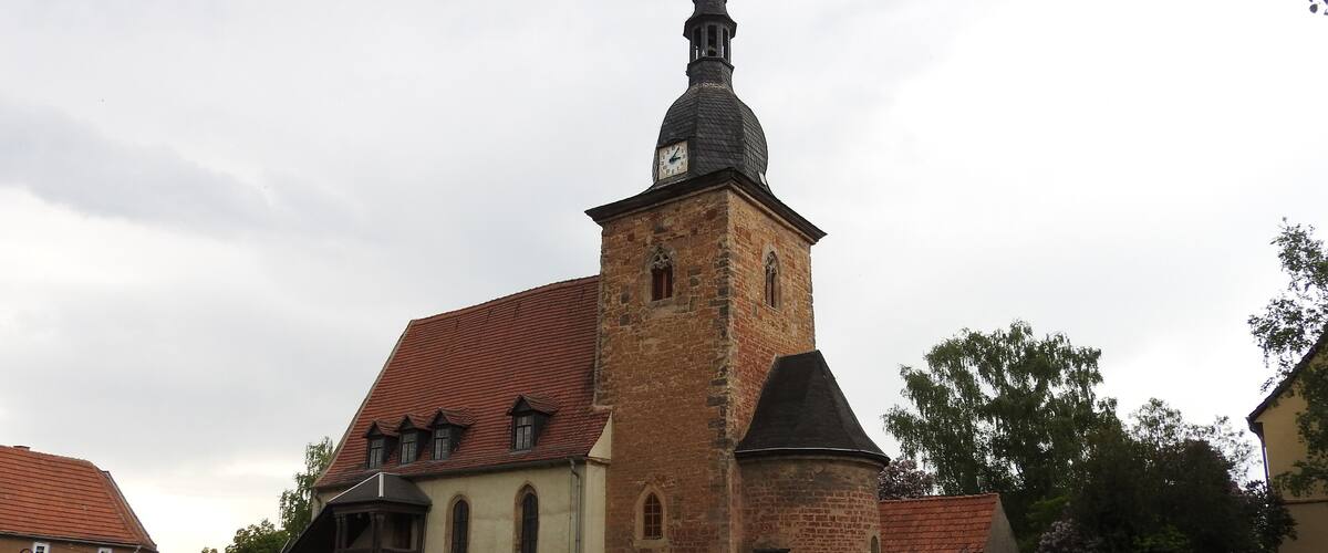 A church with a tall tower and a cemetery with headstones.