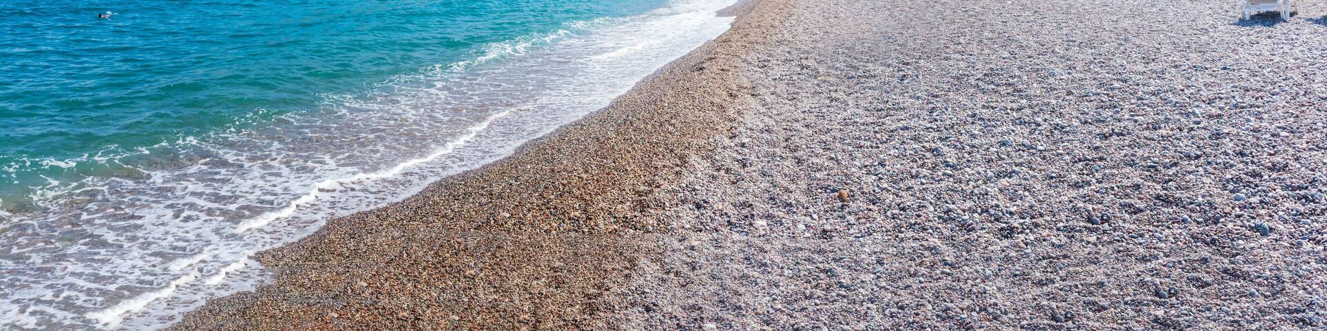 Sunbeds and umbrellas on Vlycha beach near hotel resort (Rhodes, Greece)
