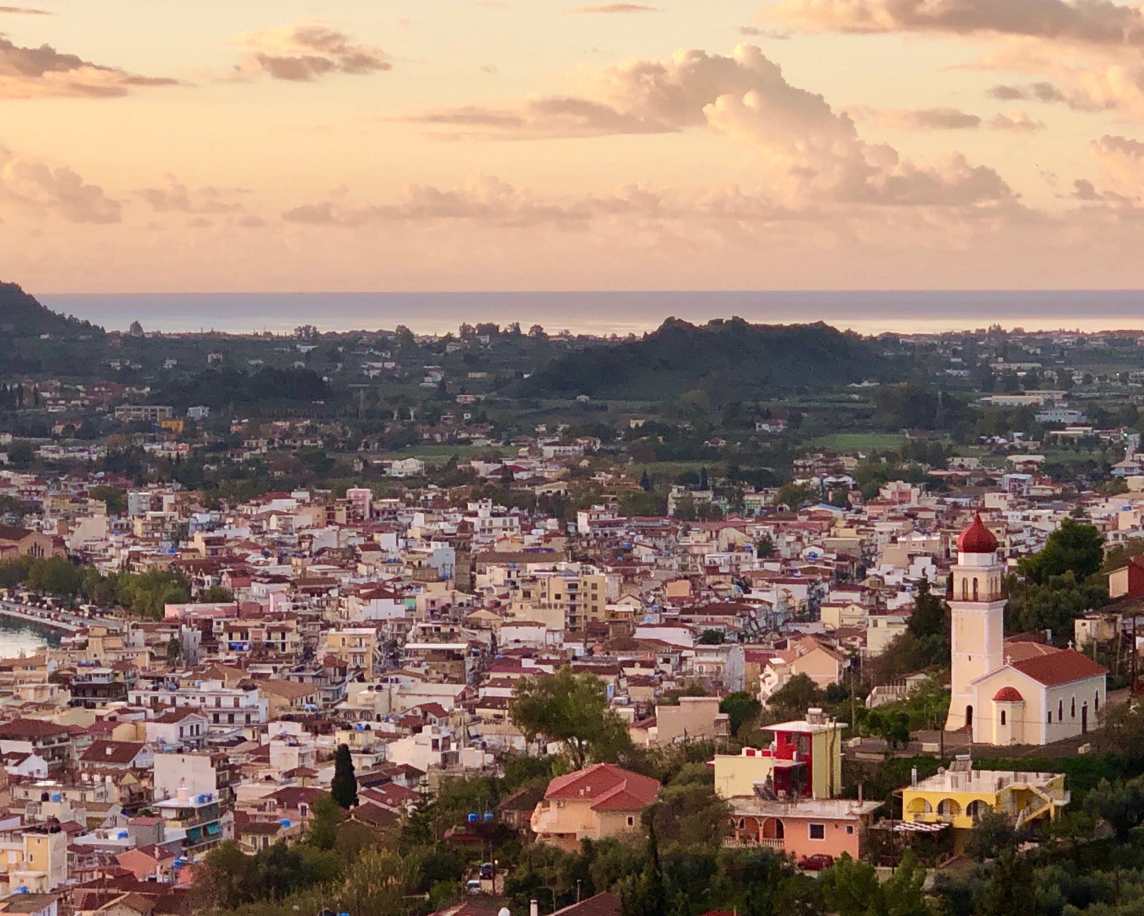 A coastal cityscape with a prominent church tower and dense urban buildings.