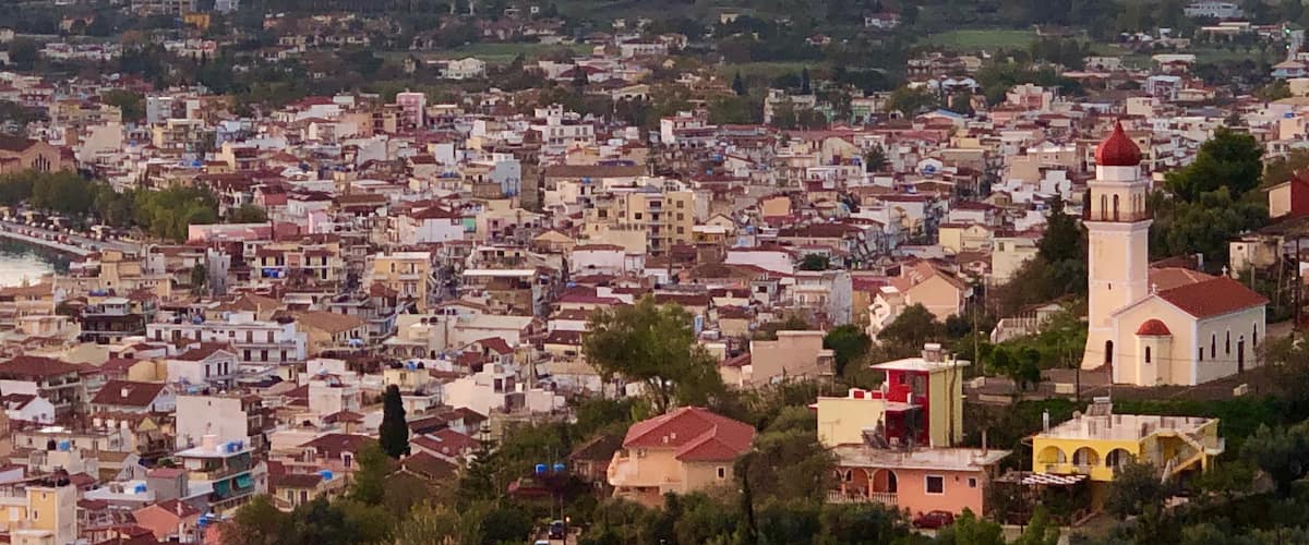 A coastal cityscape with a prominent church tower and dense urban buildings.