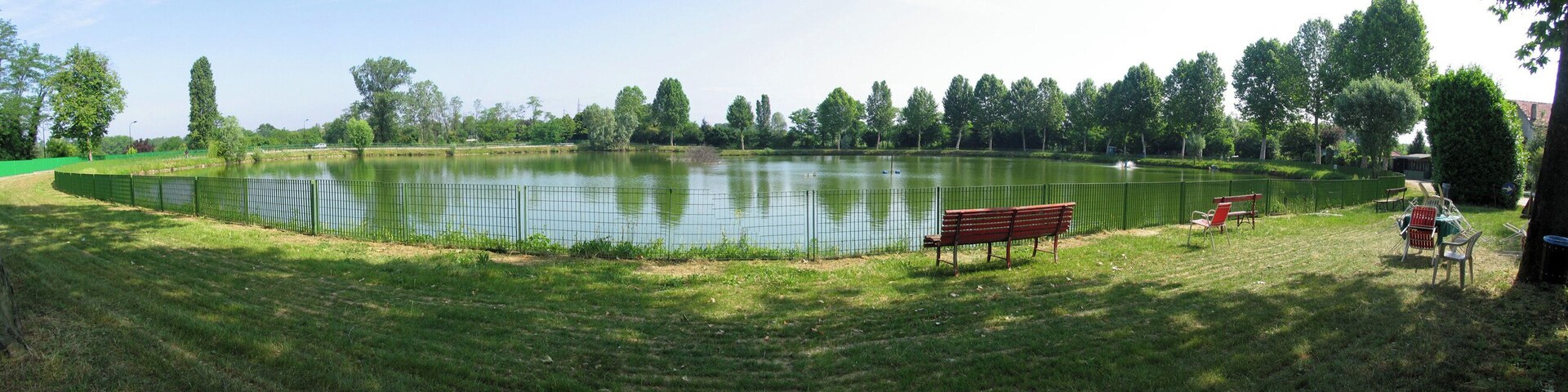 A park with a pond, benches, and trees.