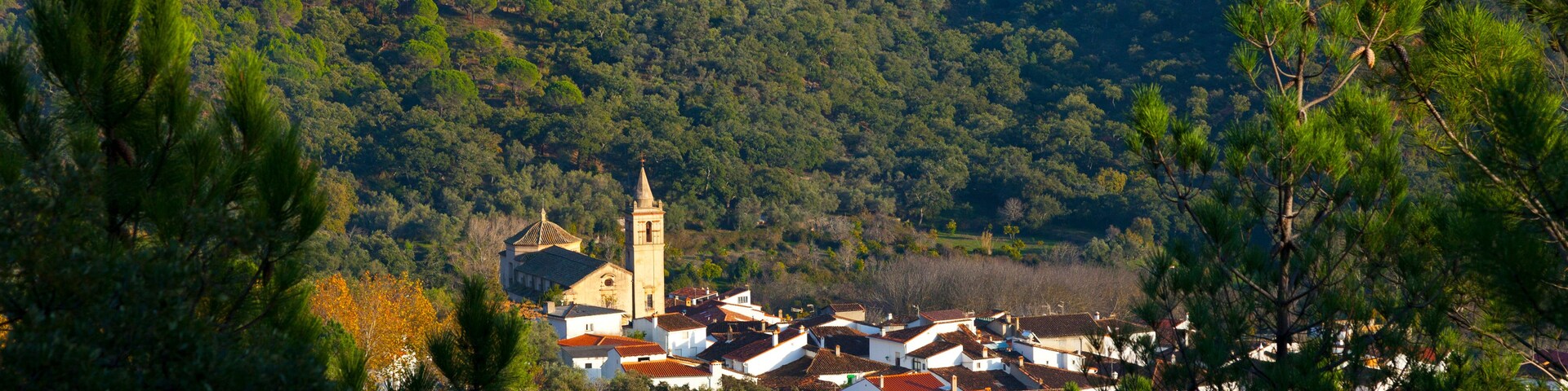 Uma aldeia situada num vale, com uma igreja e torre destacadas.