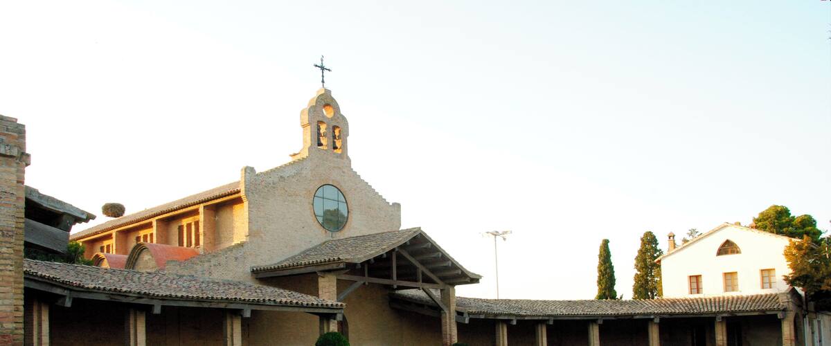 A church with a bell tower and a courtyard with a fountain.