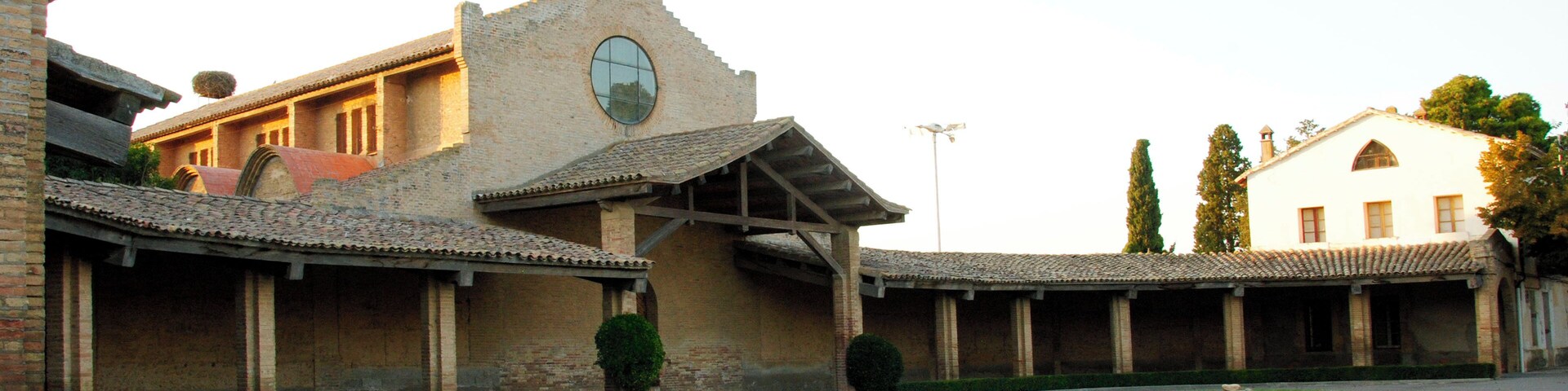 A church with a bell tower and a courtyard with a fountain.