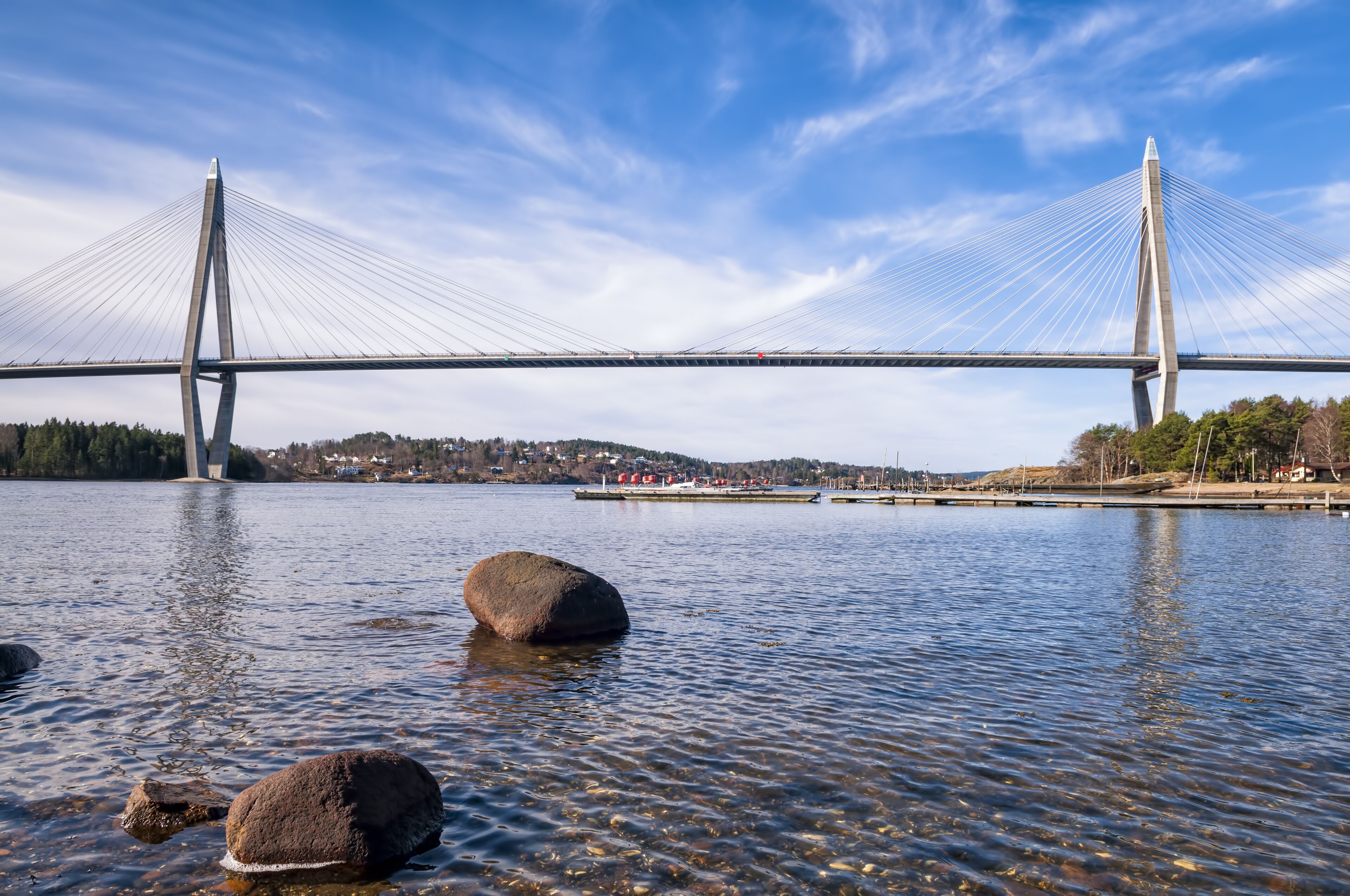 A suspension bridge over a calm lake with clear skies.