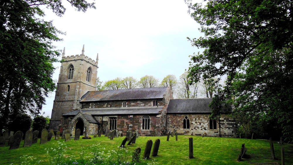 A historic church with a tall tower and a graveyard.