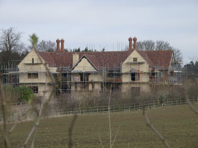 A two-story house with a red-tiled roof and a chimney, surrounded by scaffolding.