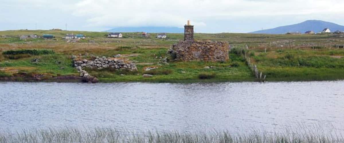 A calm lake with a stone structure and a lighthouse in the background.