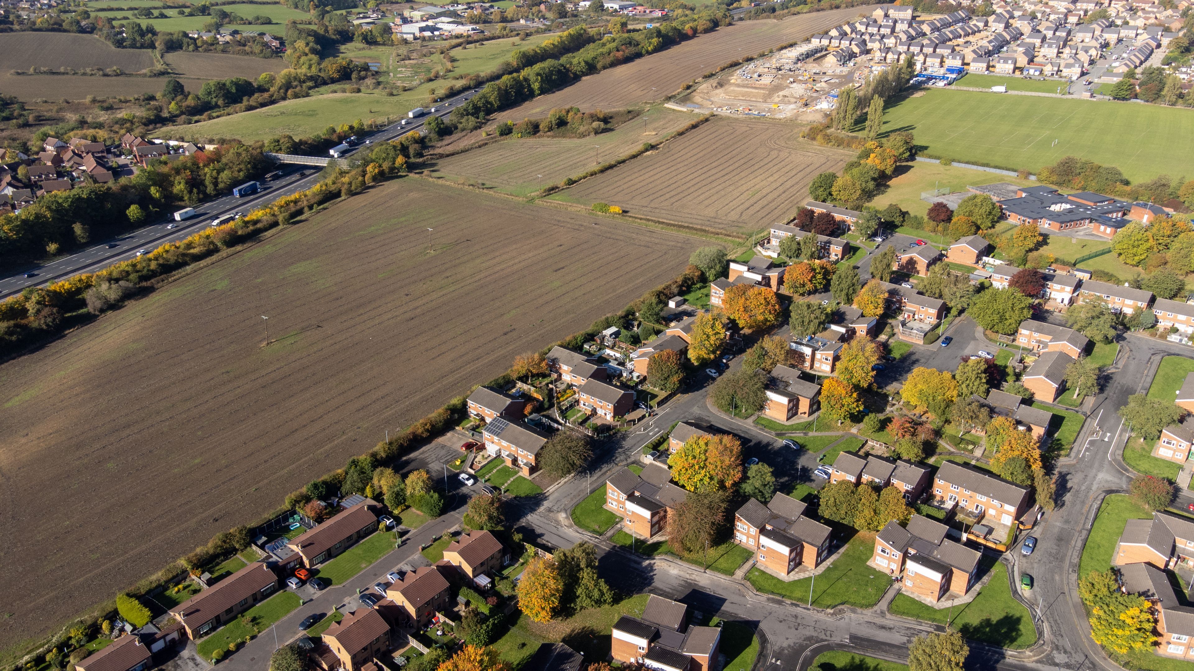An aerial view of a residential area with houses, roads, and fields.