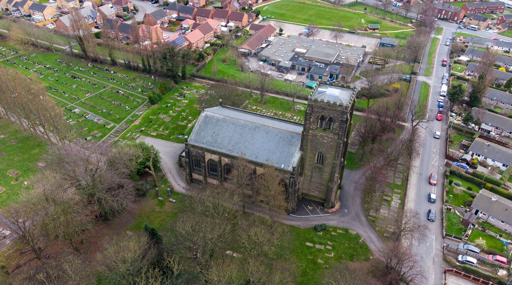 An aerial view of a cemetery surrounded by residential houses and a large industrial building.