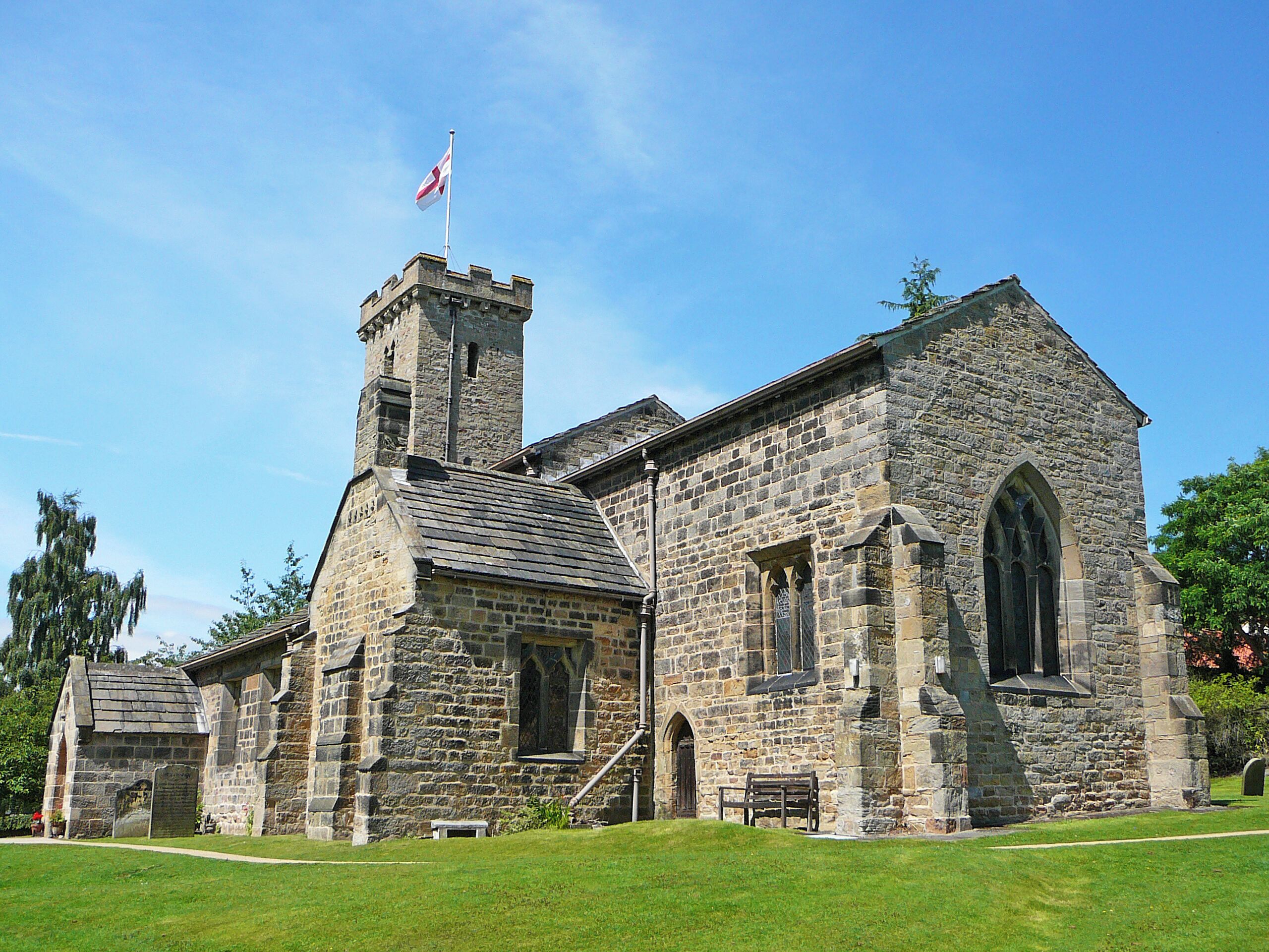 A historic stone church with a prominent tower and a flag.