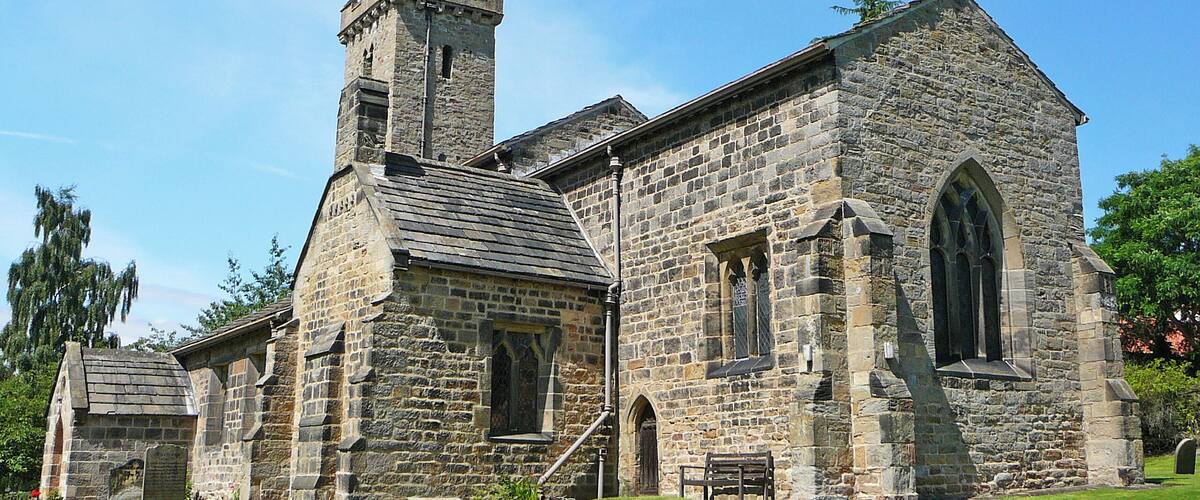 A historic stone church with a prominent tower and a flag.