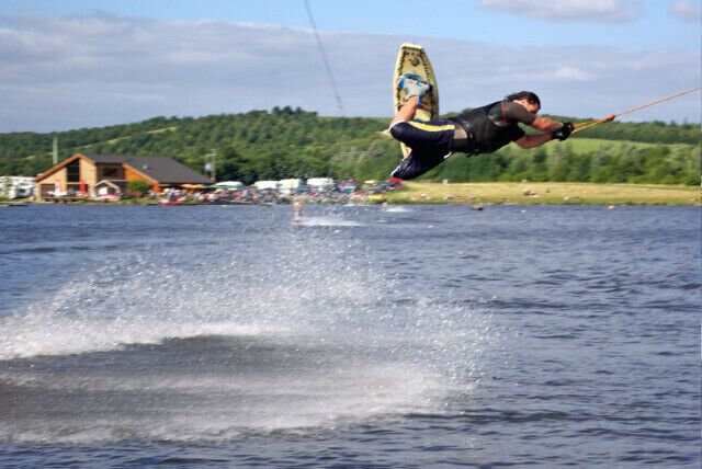Cable Waterskiing, Rother Valley Country Park One of the principal attractions at Rother Valley Country Park is the cable skiing system set up in a cordoned off area at the southern end of the large lake. Participants are pulled around on a continuous cable and there can be up to eight people using it at once. This person is using a wakeboard - by far the most common type of equipment - which allows the more confident individuals to perform spectacular acrobatics with varying degrees of success. The building in the background houses changing rooms, a pro's shop and a bar.