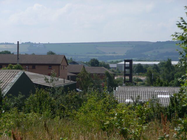 A rural landscape with buildings, a tower, and a river in the distance.