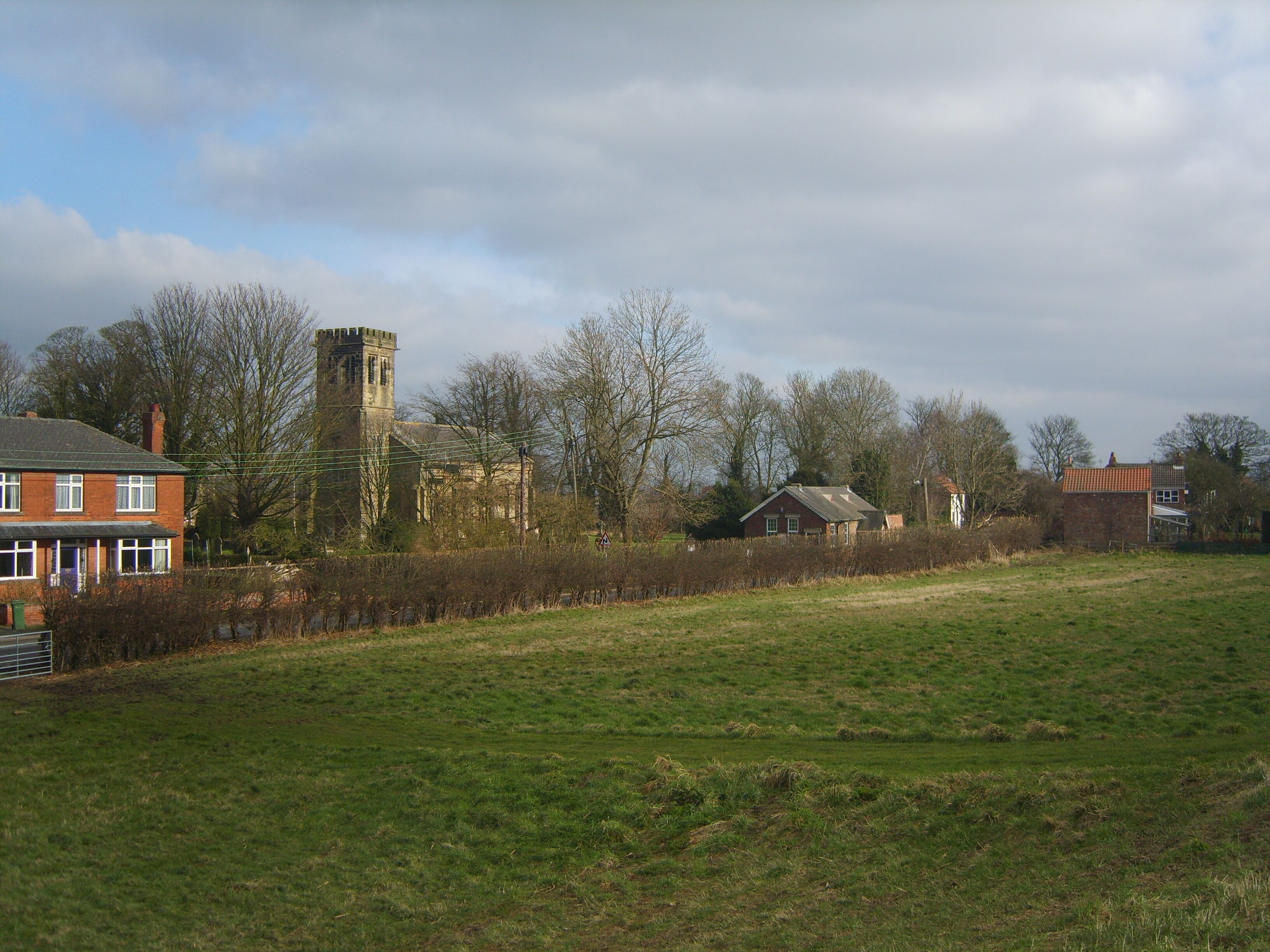 A rural landscape with a church, a tower, and residential houses.