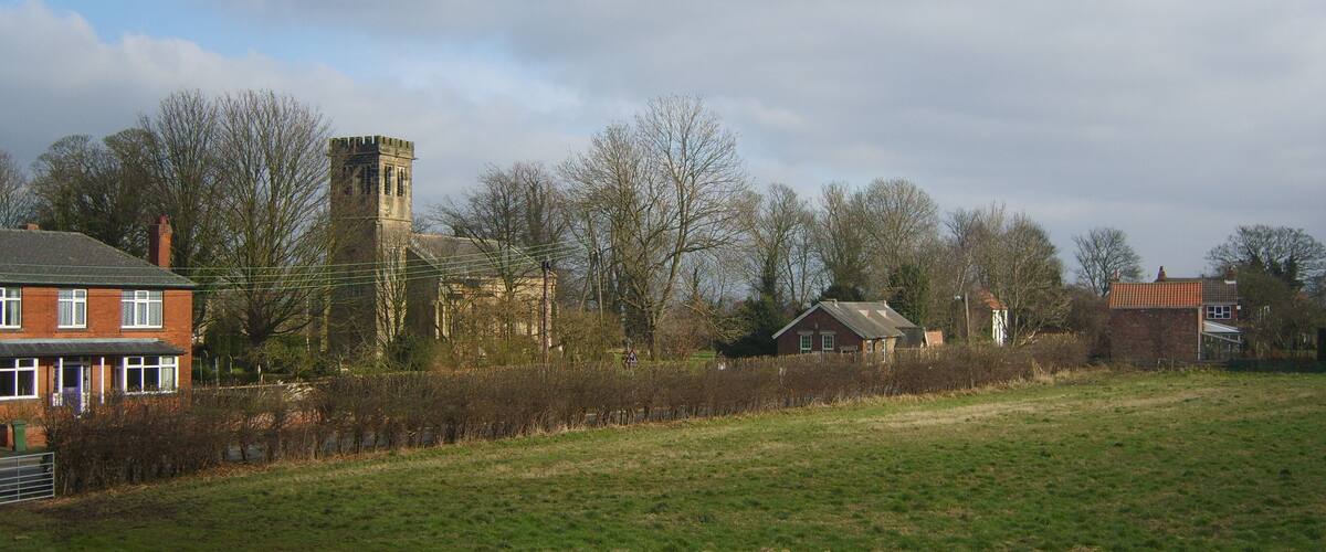 A rural landscape with a church, a tower, and residential houses.