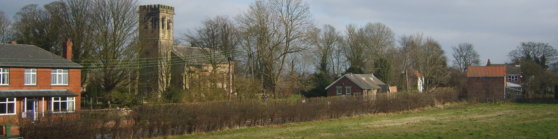 A rural landscape with a church, a tower, and residential houses.
