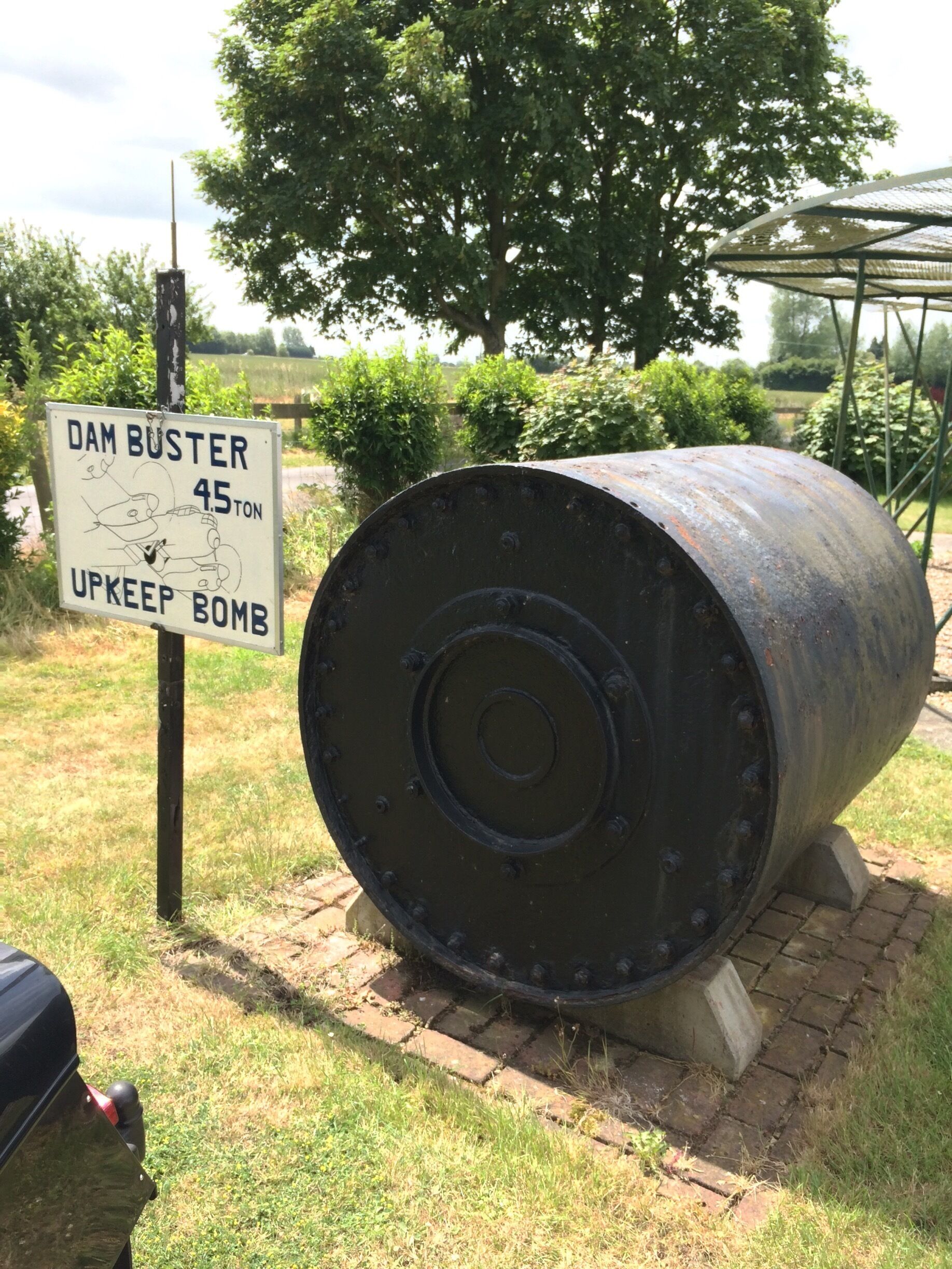 A large cylindrical bomb with a sign indicating it is a 45-ton dam buster upkeep bomb.