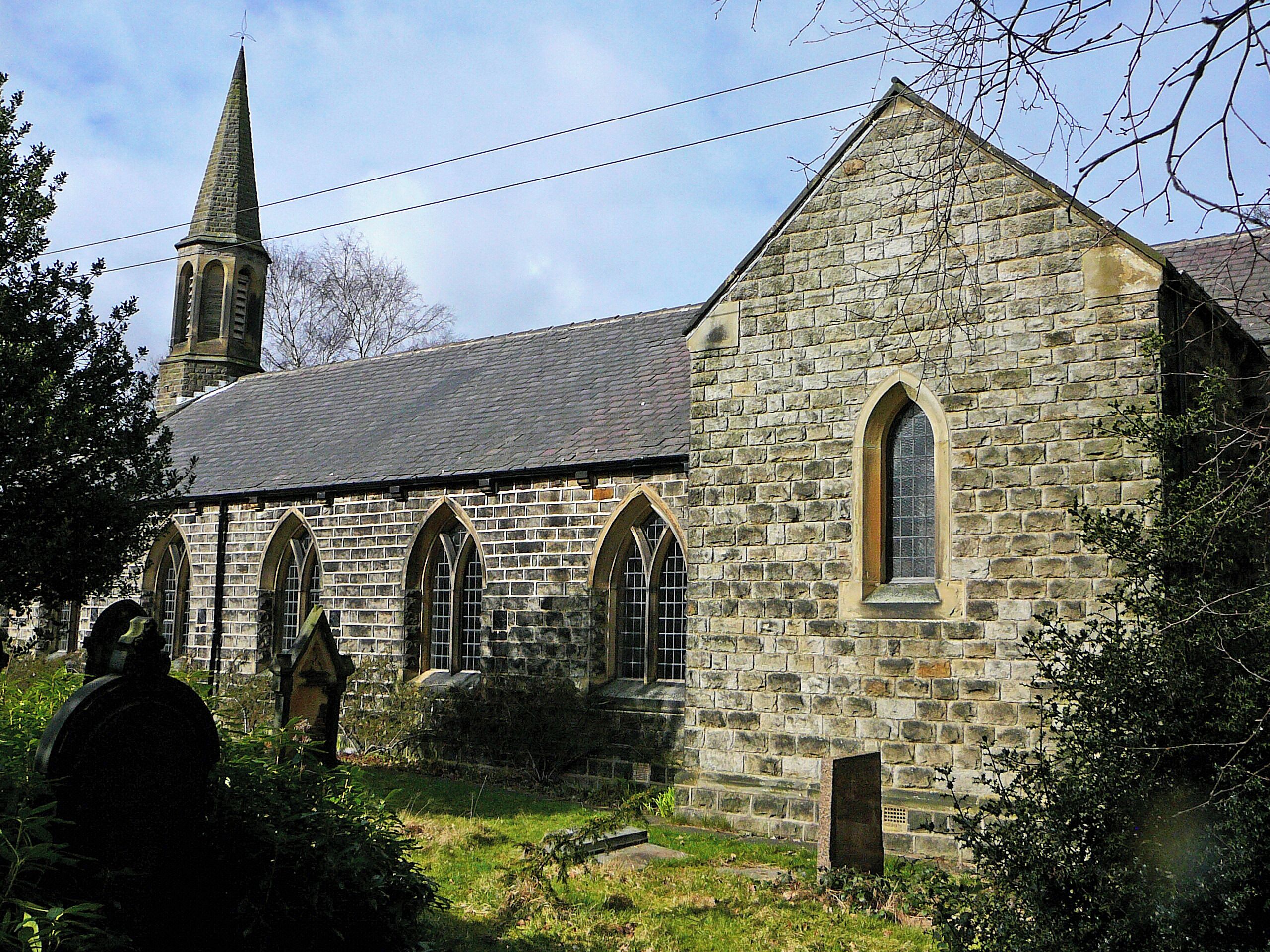 A stone church with a tall steeple and arched windows.