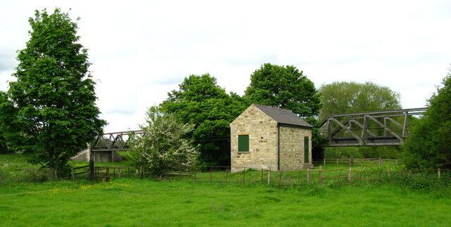 A stone building with a metal bridge in a rural setting.