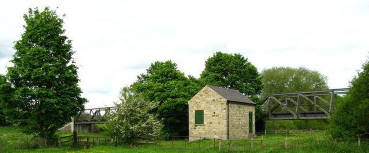 A stone building with a metal bridge in a rural setting.