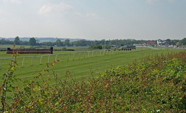 A green field with a fence and a structure in the distance.