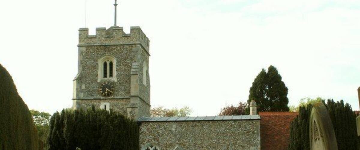 A stone church with a clock tower, a pathway, and gravestones in a cemetery.