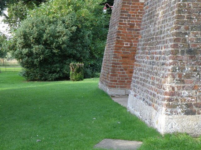 The feet of two of the buttresses of the west tower of St Mary's parish church, Conington, Cambridgeshire. An Ordnance Survey bench mark is visible on the nearer buttress.