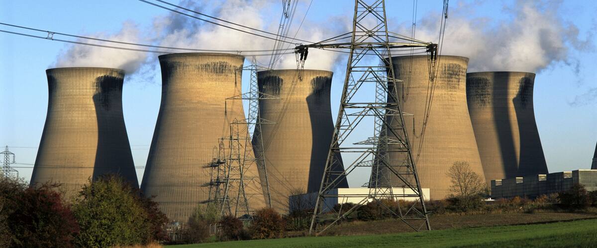 Cooling towers, a transmission tower, and a grassy field.