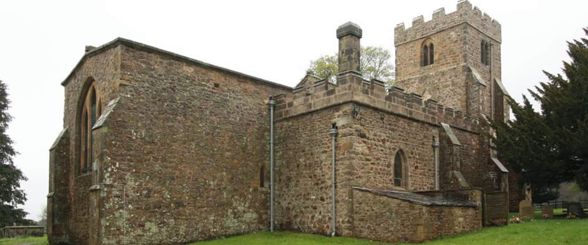 A historic stone church with a bell tower and arched windows.