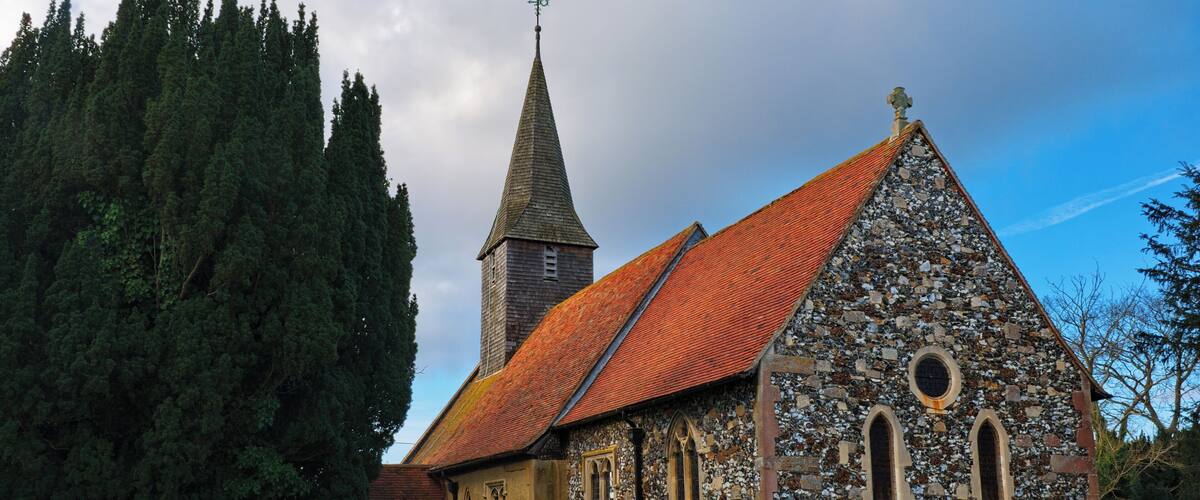 A stone church with a red-tiled roof and a tall steeple.