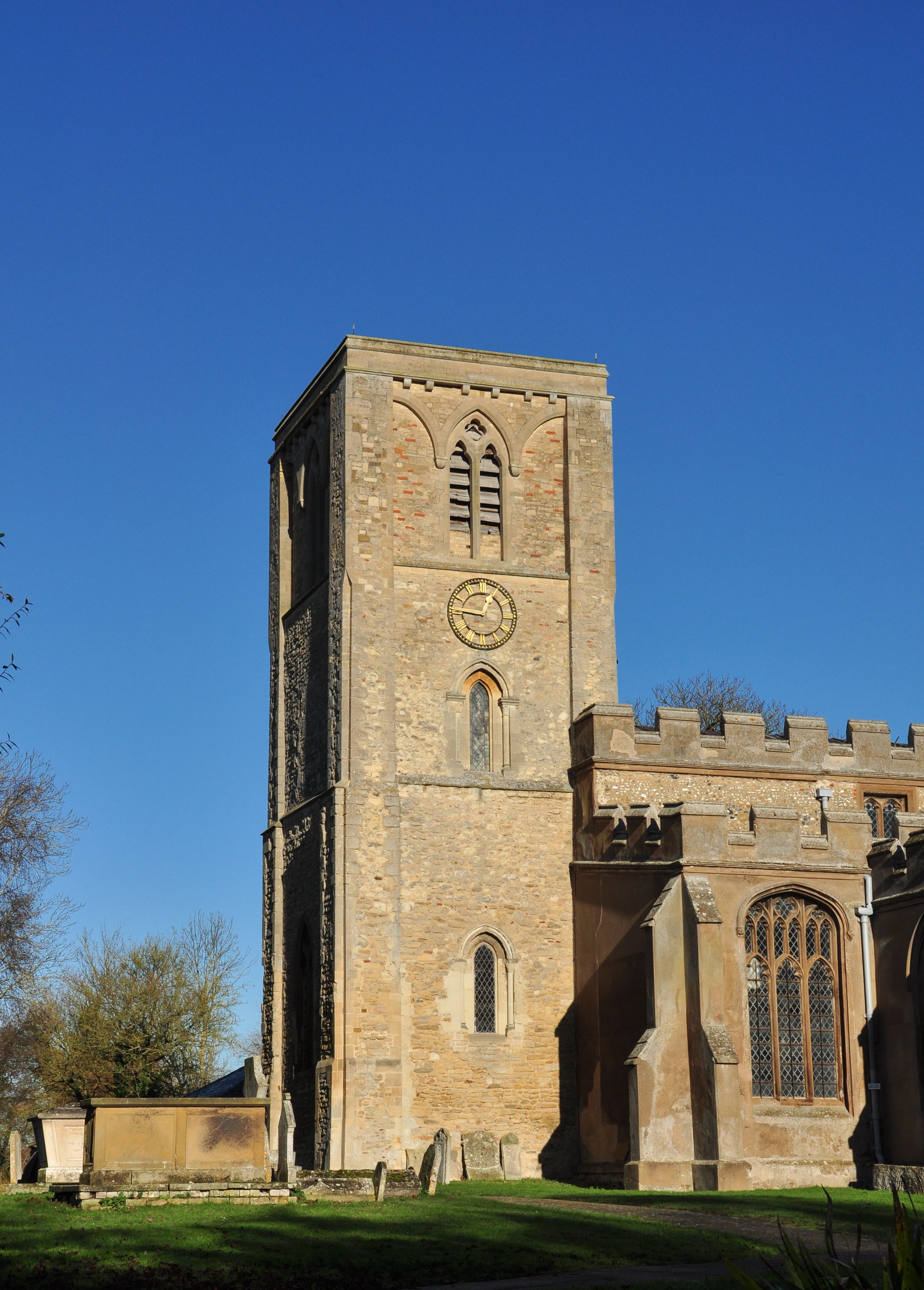 A historic stone tower with a clock, arched windows, and a castle-like structure with battlements.