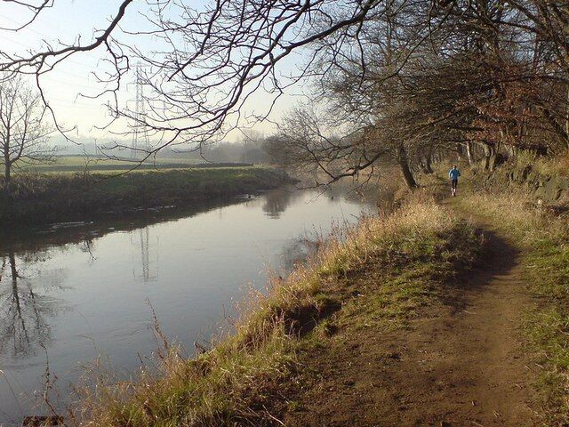 River Aire, February A solitary jogger follows the footpath along the river, towards Broadway. The railway is beyond the wall on the right.