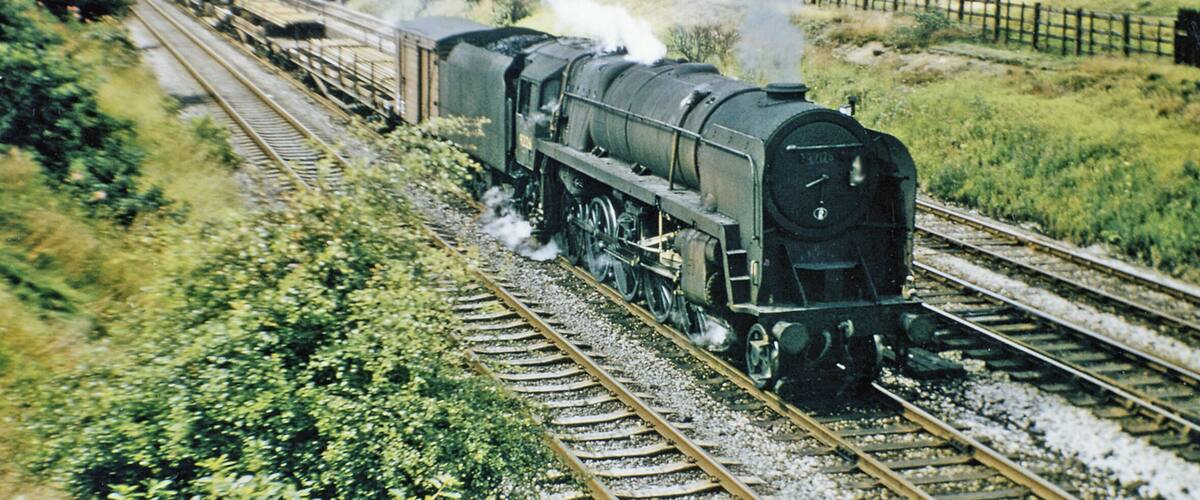 A steam locomotive on railway tracks with a town in the background.
