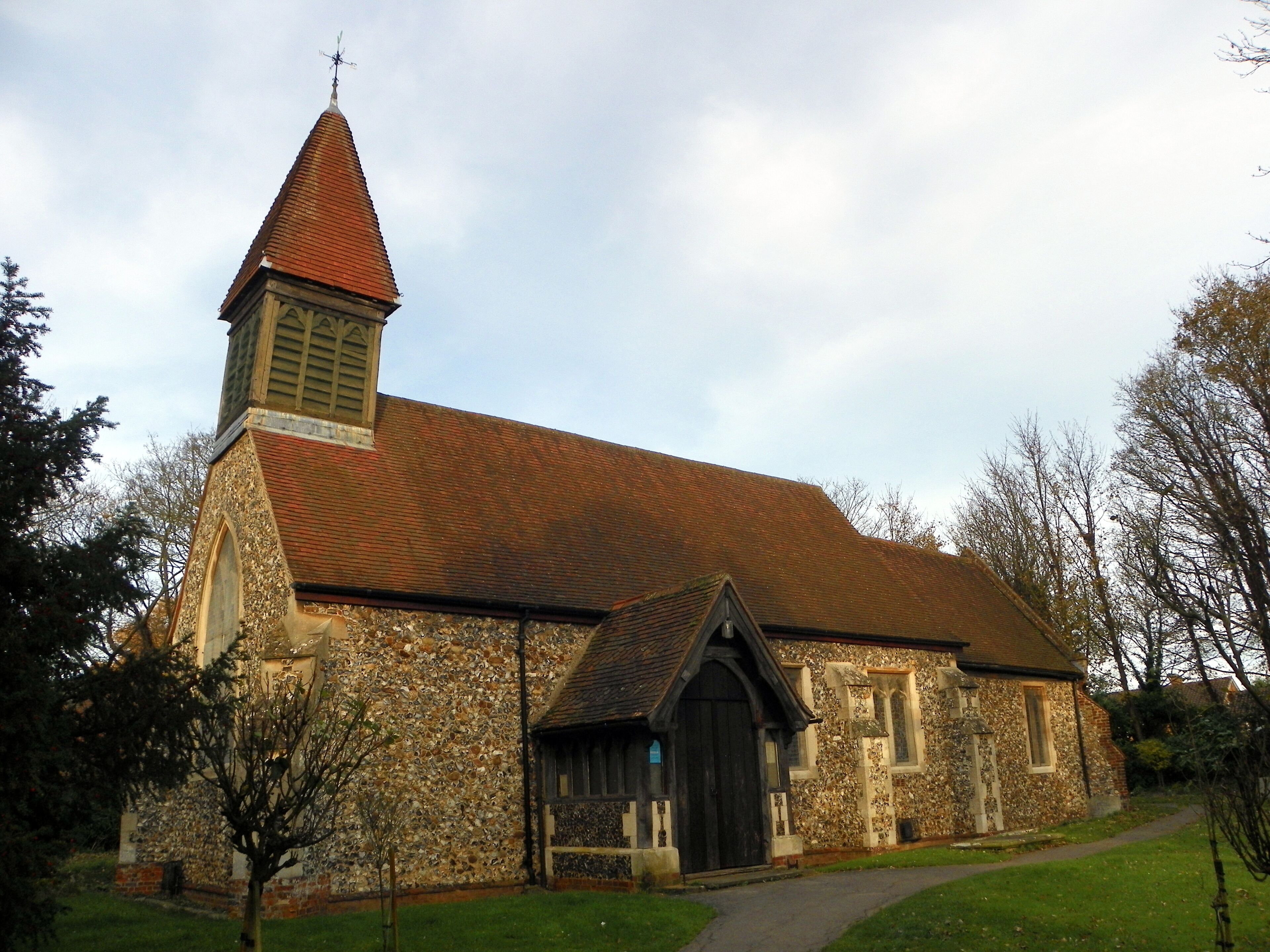 A church with a stone facade, a red-tiled roof, and a pointed steeple.
