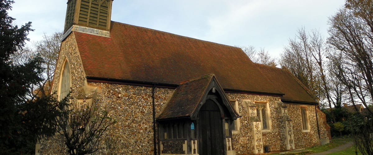 A church with a stone facade, a red-tiled roof, and a pointed steeple.