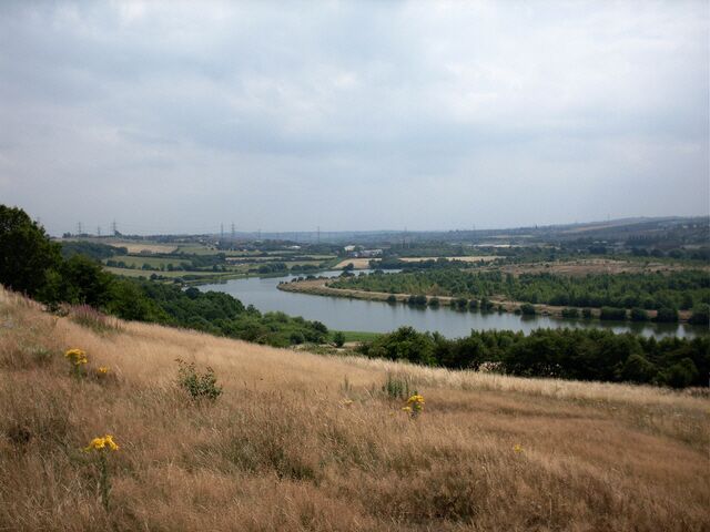A river winding through a hilly landscape with fields and trees.