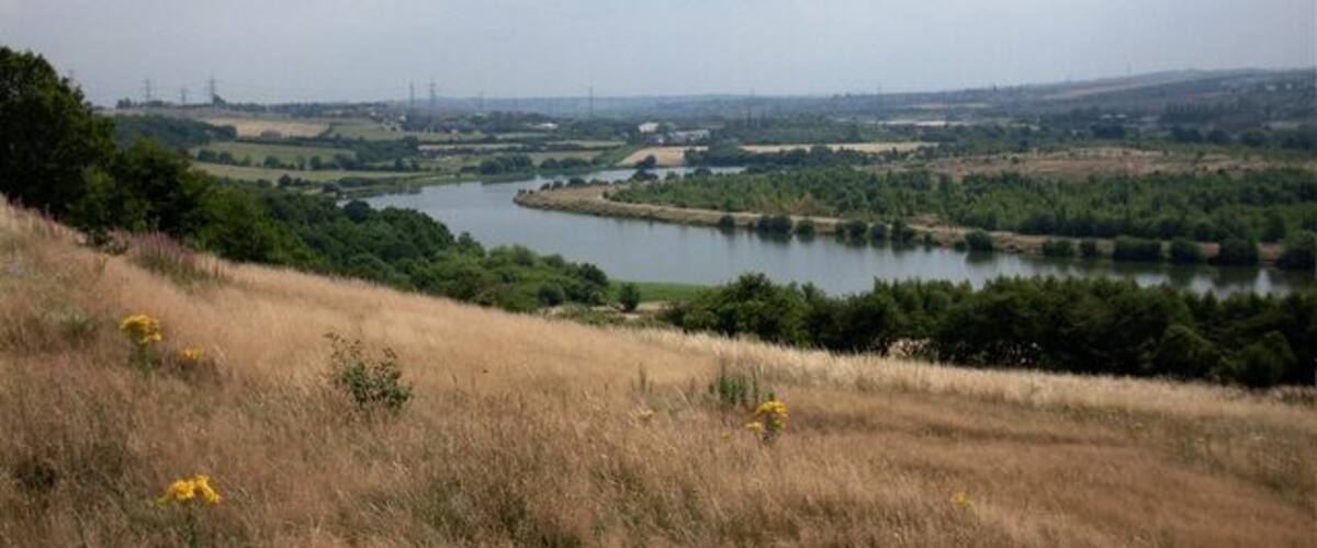A river winding through a hilly landscape with fields and trees.
