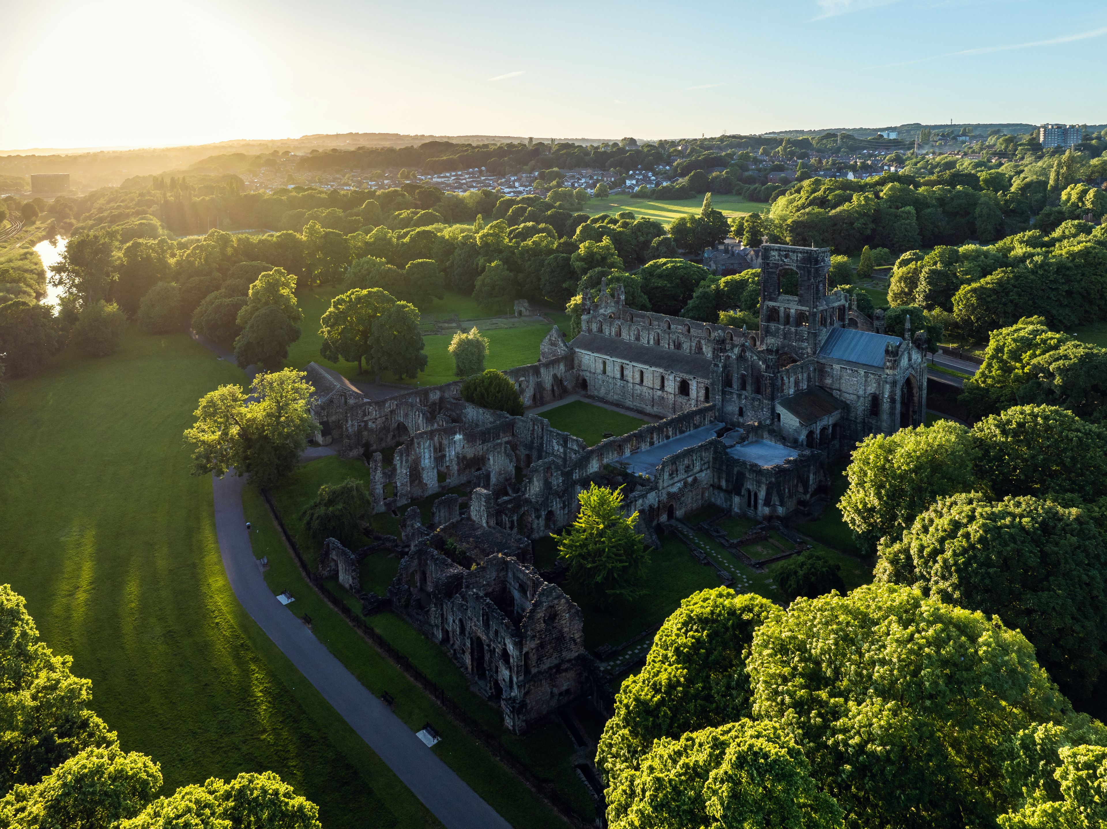 Une vue aérienne d’un château historique, entouré d’une végétation luxuriante et d’une pelouse bien entretenue.
